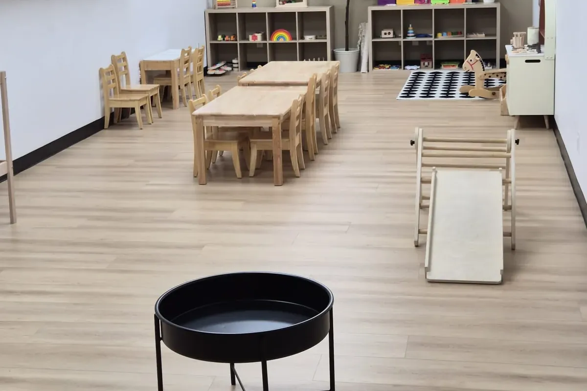 A classroom at The Stars with low wooden shelves of Montessori materials and child-sized tables and chairs