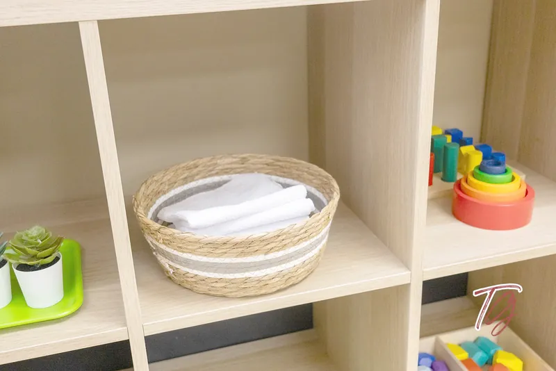 A basket of cloths and stacking rings on a shelf