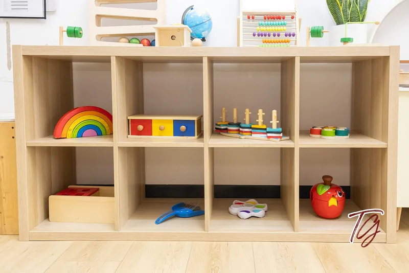 A cube shelf with a wooden rainbow, a drawer box and stacking toys