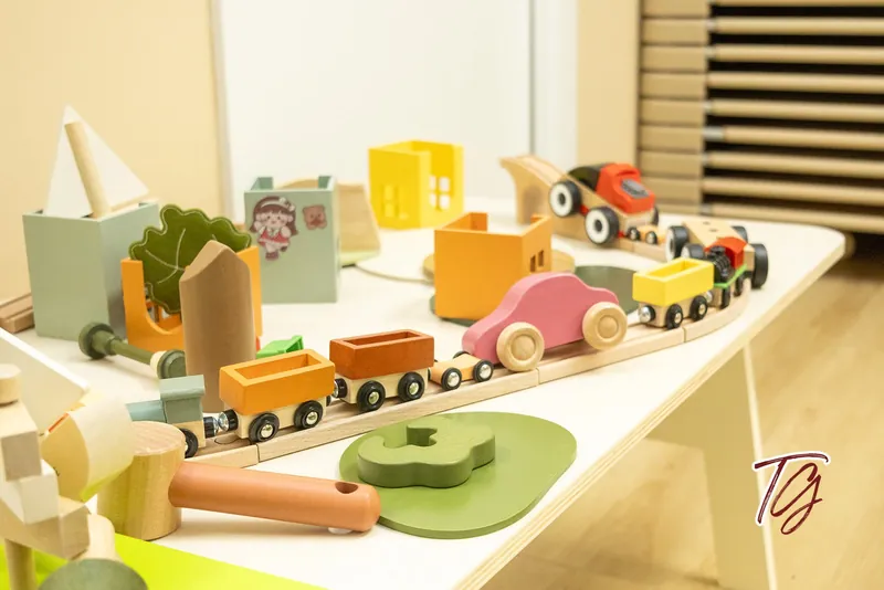 A wooden train set with toy cars and little houses