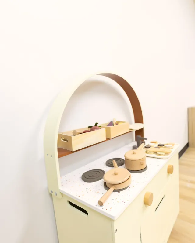 A wooden play kitchen in a classroom corner