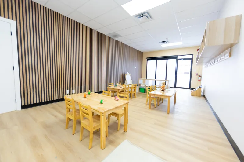 One of our classrooms, with a slatted wood feature wall, low wooden tables and chairs, and large windows